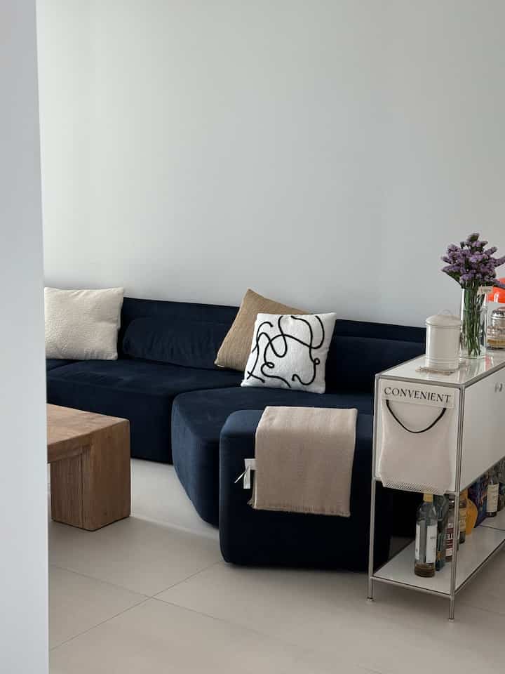 ネイビーソファとウッドのコーヒーテーブルが配置されたホワイトトーンのミニマルで居心地の良いリビング