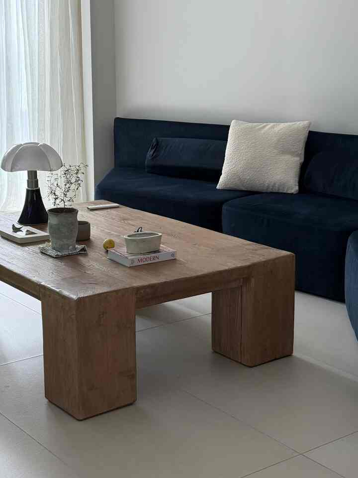 ネイビーカラーのソファと木目調のコーヒーテーブルが配置されたシンプルモダンなリビングスペース