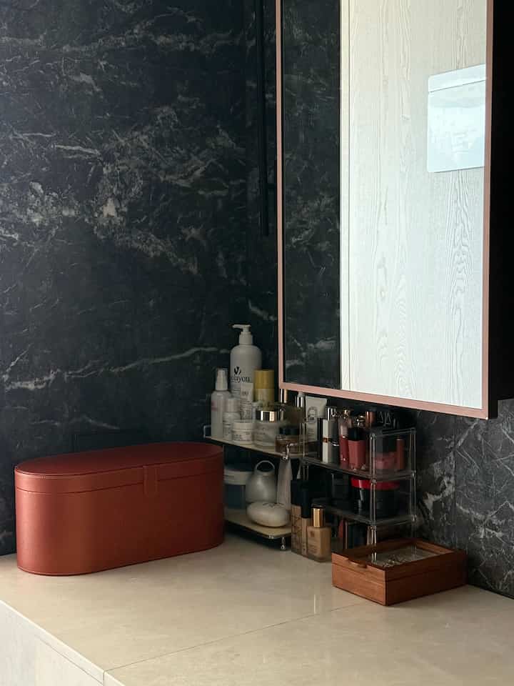 ベージュの大理石の化粧台と黒い大理石の壁が配置されたミニマルなバスルーム空間