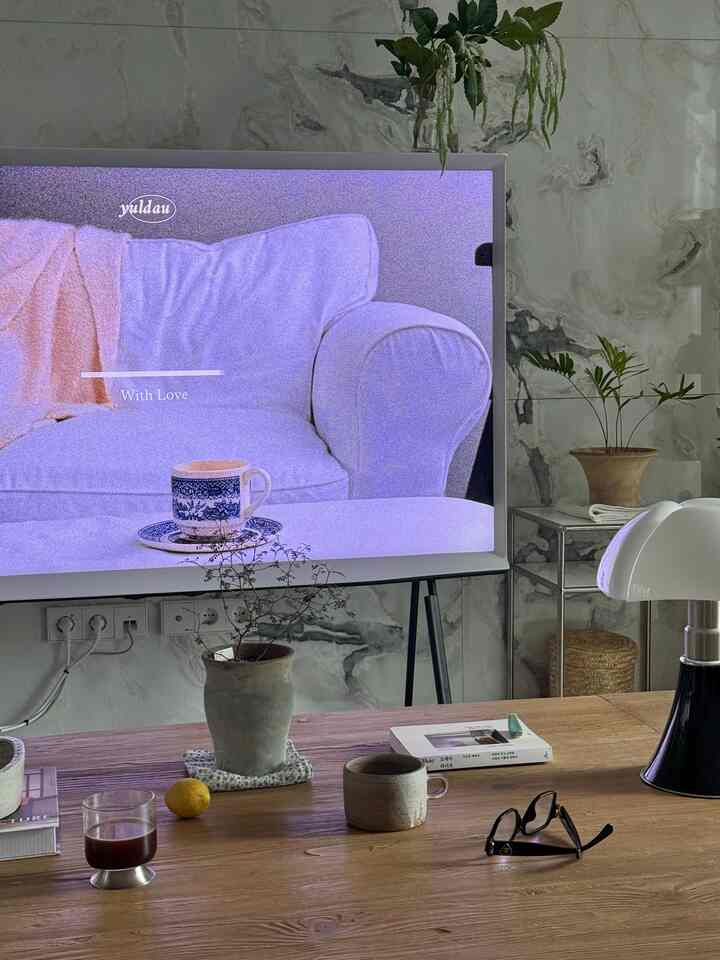 ナチュラルな色調のリビング、木製コーヒーテーブルとテーブルランプ、植物が配置された落ち着いた空間