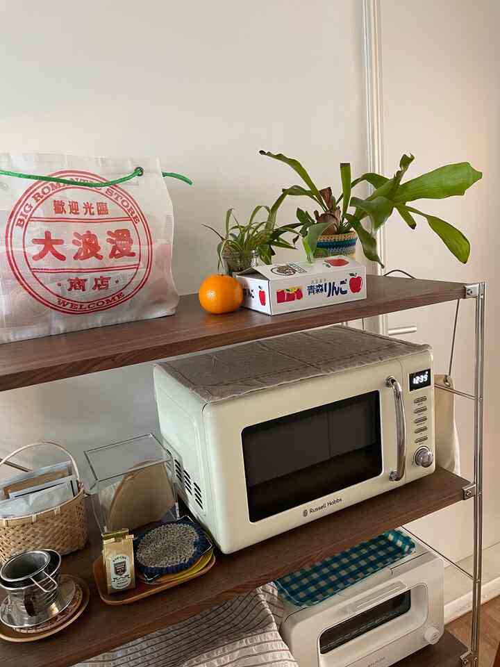 白い壁と茶色のウッドシェルフが配置されたナチュラルなキッチンスペース、小型家電が整然と置かれた雰囲気のあるインテリア