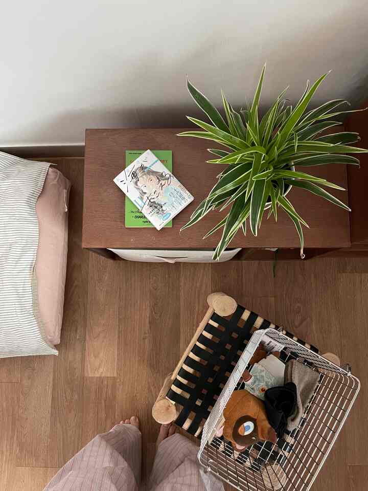 木目調の床とナイトテーブルを配したナチュラルな寝室、緑の植物がアクセントになっている雰囲気のあるインテリア