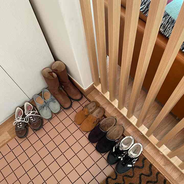 木目調の間仕切り壁と多様な靴が置かれた狭い玄関スペース