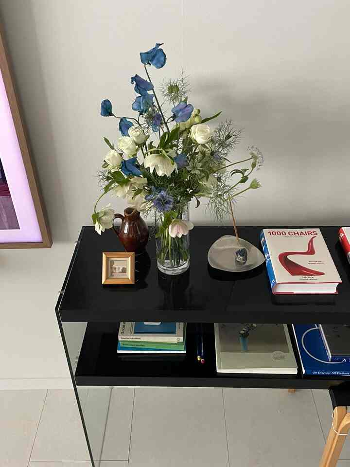 黒い棚の上に花瓶、本、額縁が置かれたシンプルなリビングのインテリア