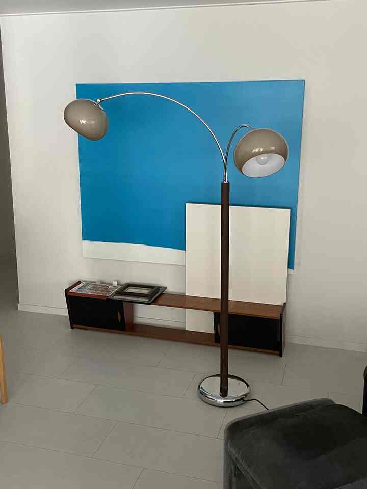 明るい青のウォールアートと木目調のコンソールがあるナチュラルモダンなリビング、中央にクロームとブラウンのフロアランプ配置