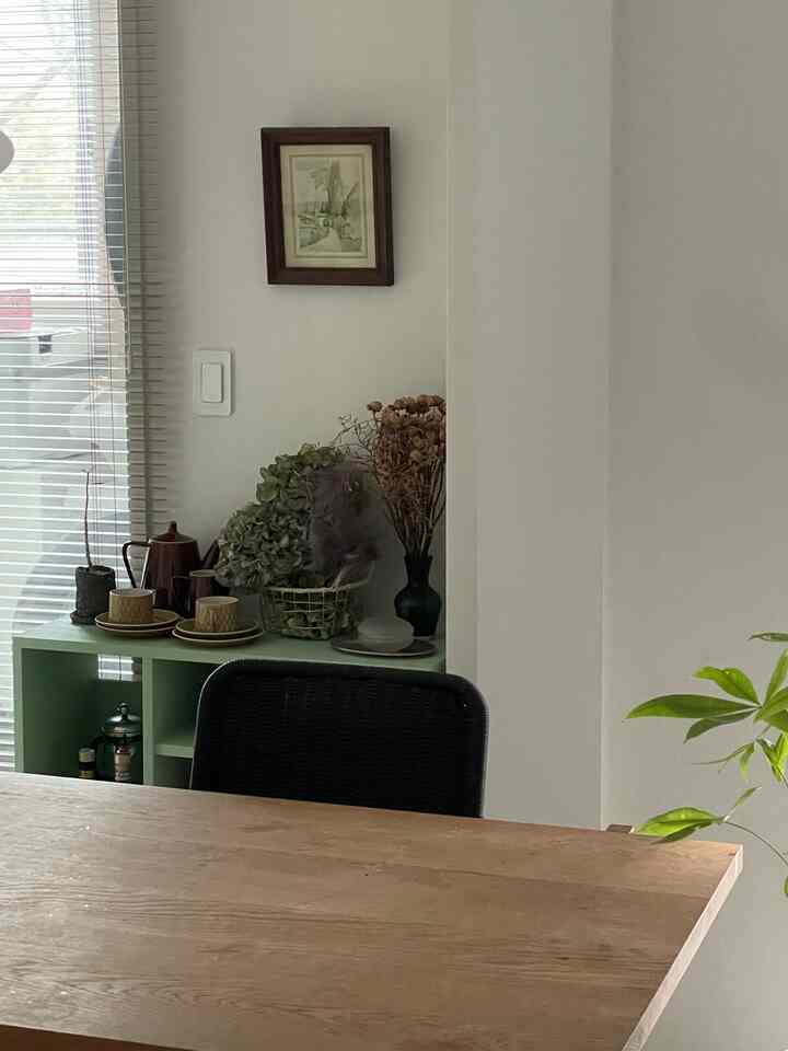 白い壁とミント色のキャビネットが調和したフレンチカントリースタイルのダイニング空間、ヴィンテージの装飾と木製テーブルが温かみのある雰囲気を醸し出している。