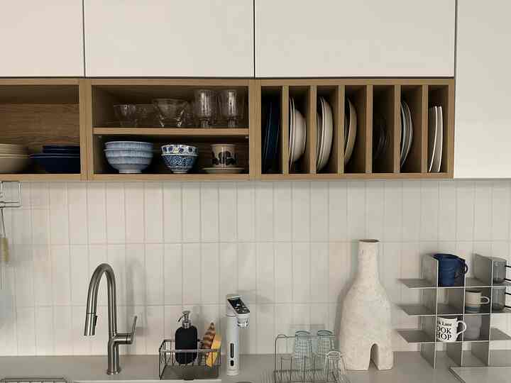 白と木目調が調和したキッチン、整然と並べられた皿やボウルがあるモダンな空間