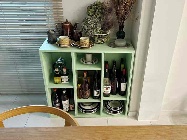 ミント色のキャビネットが中央に配置されたキッチンスペース、ワインボトルや皿が整頓され、落ち着いたヴィンテージの雰囲気