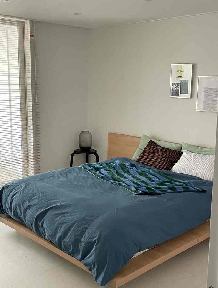 ナチュラルカラーの寝室、ウッドベッドとブルーの寝具が配されたシンプルで落ち着いた空間