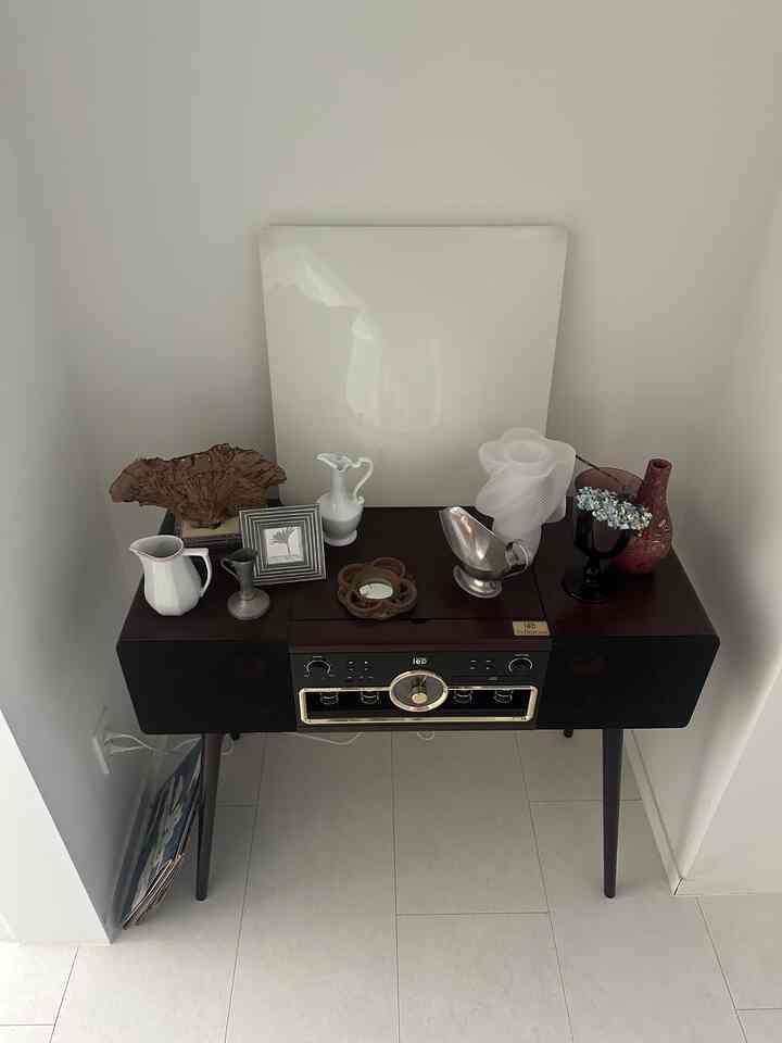 白い壁に囲まれたブラウンのコンソールテーブルにオールインワン真空管オーディオと様々な装飾オブジェが配置された雰囲気のある空間