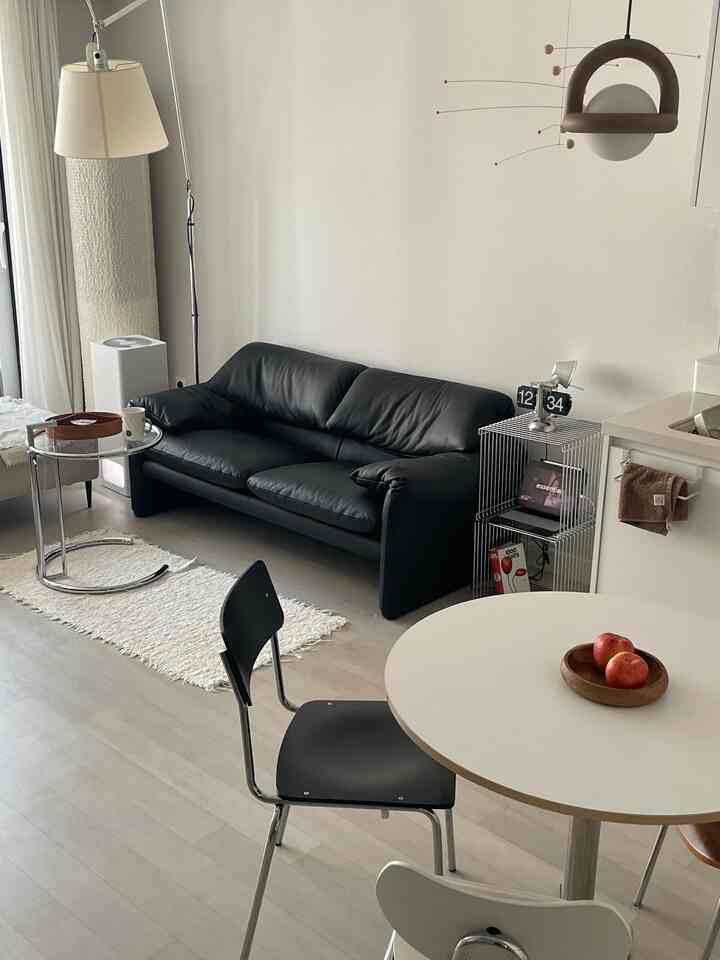 モダンでシンプルなリビング、ブラックのソファと白いテーブルが調和した洗練されたインテリア