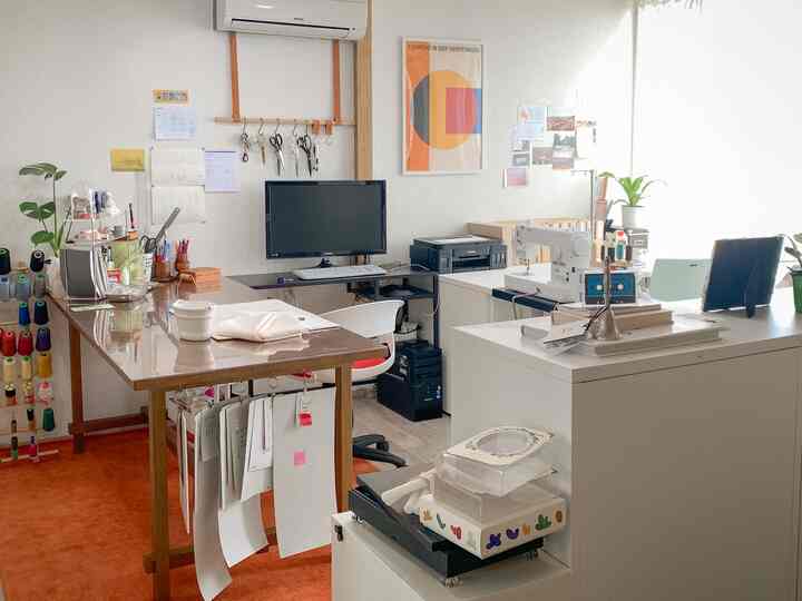 ウッドトーンとホワイトのホームオフィス作業空間、机とミシン、コンピューターが配置された温かみのあるインテリア