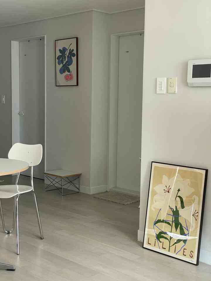 アイボリー調のリビング、シンプルなダイニングチェアとポスターが配置された落ち着いたミニマルな空間