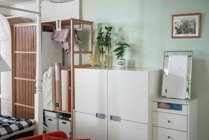 ホワイトとウッドトーンの調和が取れたリビング、クローゼットとチェスト、化粧台の鏡と植物が配置された清潔感ある空間