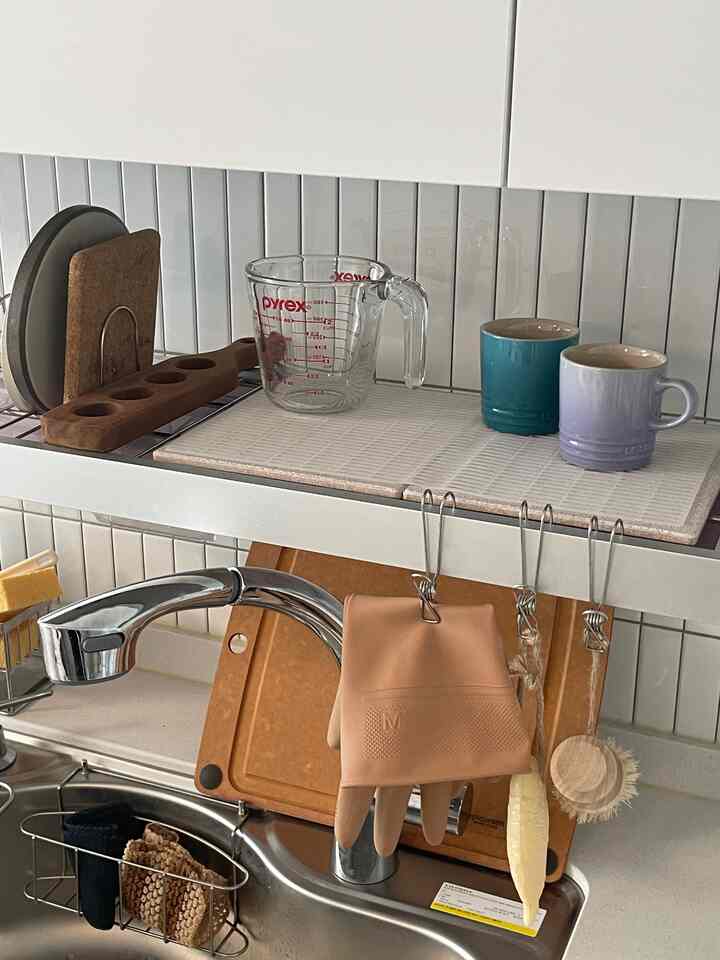 白いタイルと木目調のまな板が調和するキッチン、整頓された食器乾燥スペースにリーフホームの珪藻土マットが配置されている