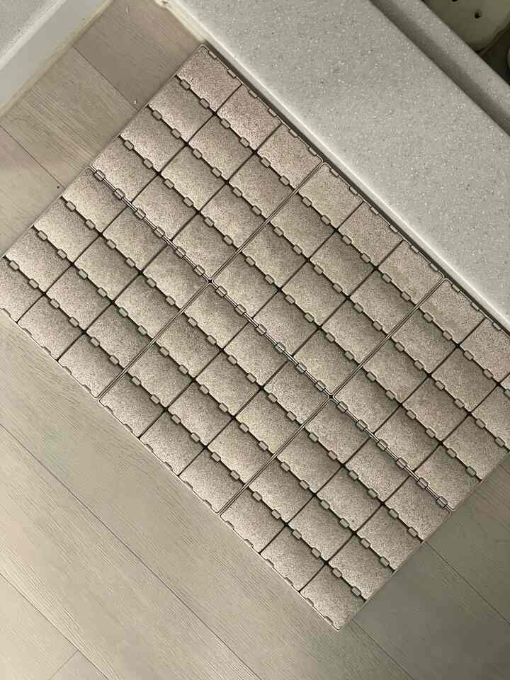 ベージュのトーンのバスマットが明るい木製の床に敷かれている