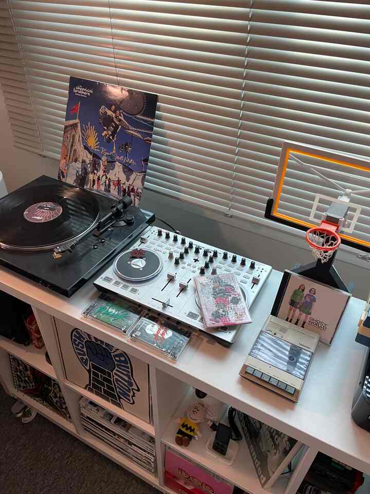 白を基調とした小さな音楽とゲームスペース、白いブラインドの前にDJ機器とレトロな音楽アイテムが配置されたインテリア