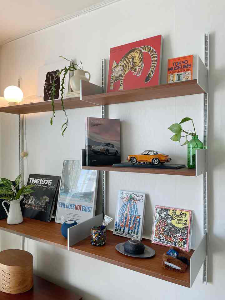 白と木目調が調和した壁棚に本や装飾品、植物が配されたシンプルモダンなインテリア