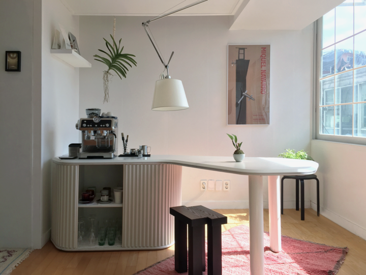 明るくナチュラルなトーンのホームカフェ空間で、コーヒーマシンとペンダントライト、白いテーブルが配置されたモダンなインテリア
