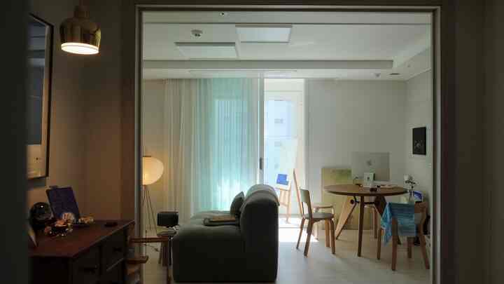 柔らかなブルーカーテンと木目調家具が配置されたナチュラルモダンなリビング兼ホームオフィス空間