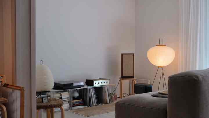 ライトグレーのソファと白い壁、フロアランプが配置されたレトロな雰囲気のリビング