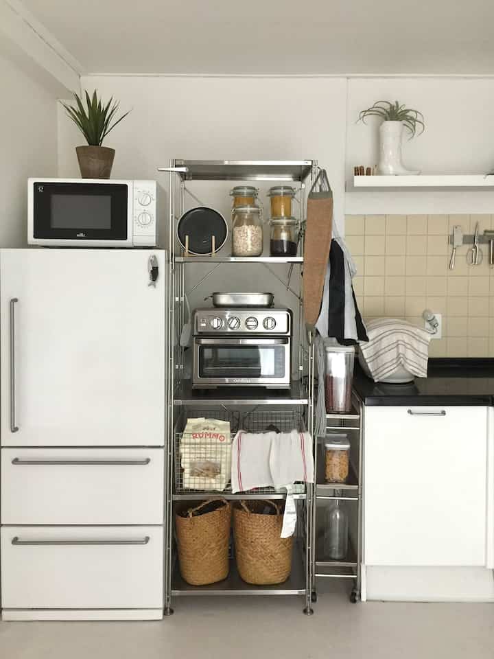 白を基調としたキッチン空間、無印良品の冷蔵庫とステンレス棚が配置された印象的なインテリア