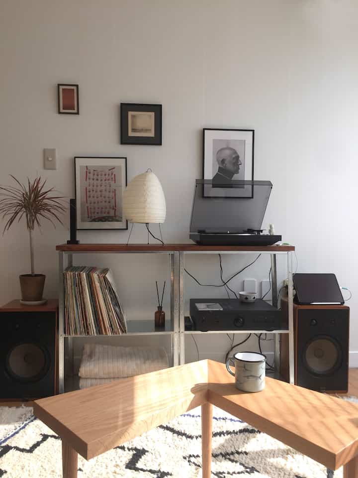 白い壁と木目調家具、スピーカーとターンテーブルが配置されたナチュラルなオーディオルーム