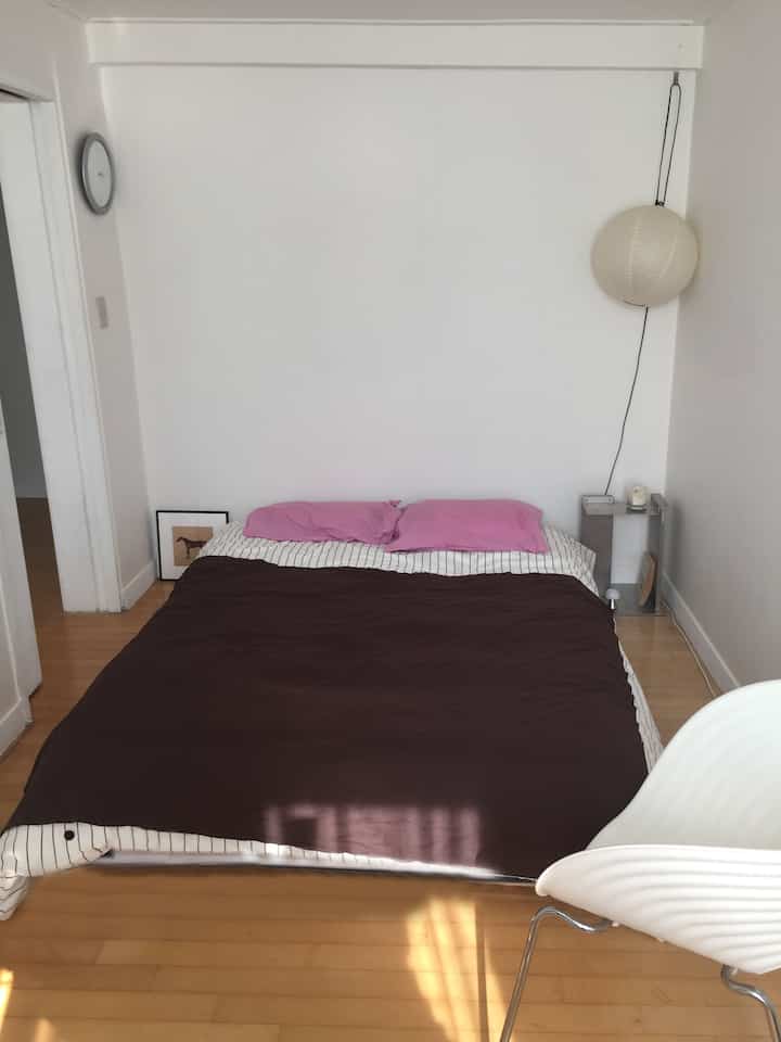 白い壁と木の床、シンプルでロータイプのベッドが配置された寝室のインテリア