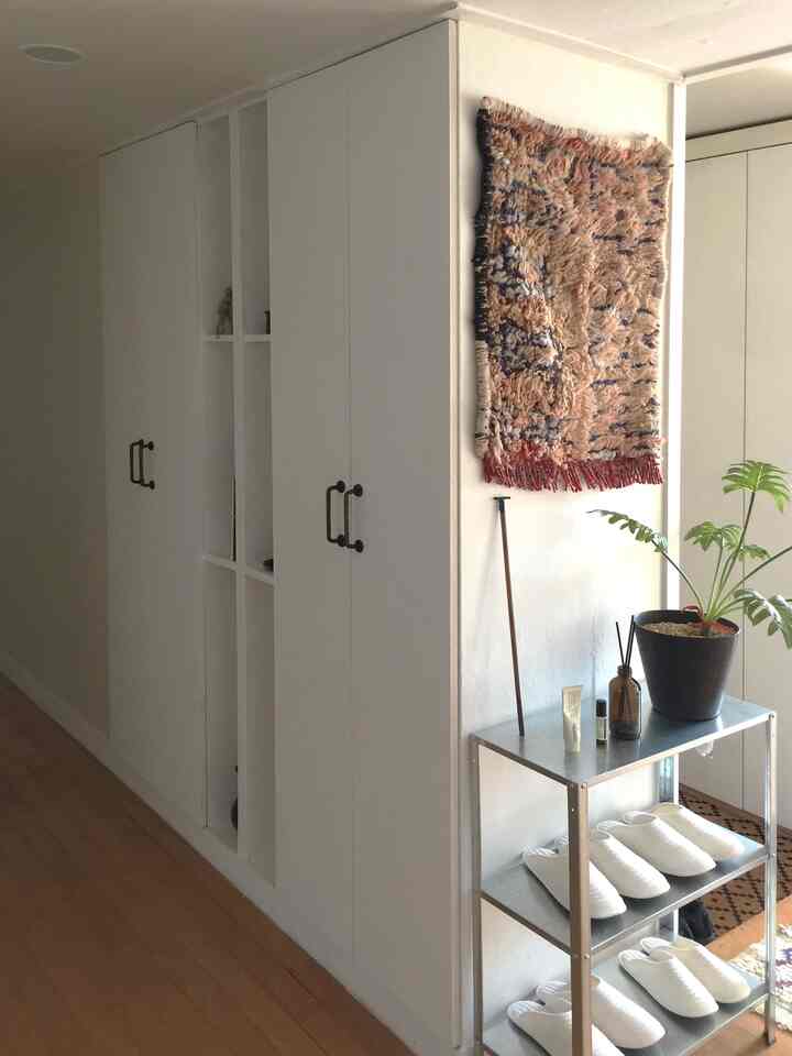 白い壁とキャビネットが配置された玄関の廊下、木目調の床とミニマルな収納が印象的な空間