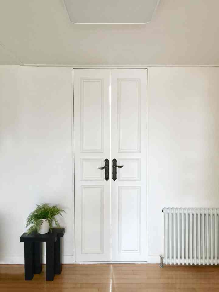 ホワイトと木目調が調和する間仕切り空間、ブラックのスツールとヴィンテージラジエーターがアクセントのシンプルなインテリア