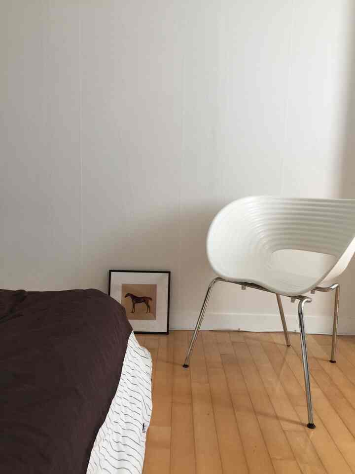 白を基調とした寝室にビトラチェアとダークブラウンの寝具が配置されたシンプルなインテリア