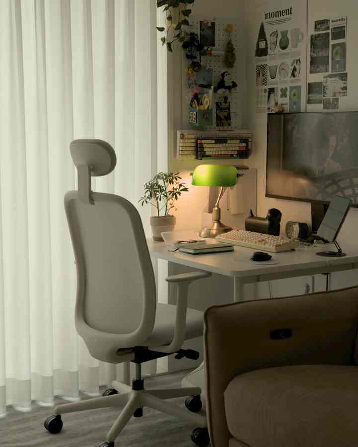 ホワイトとナチュラルカラーが調和したリビングのホームオフィス、緑のテーブルランプと植物が印象的な落ち着いた作業空間