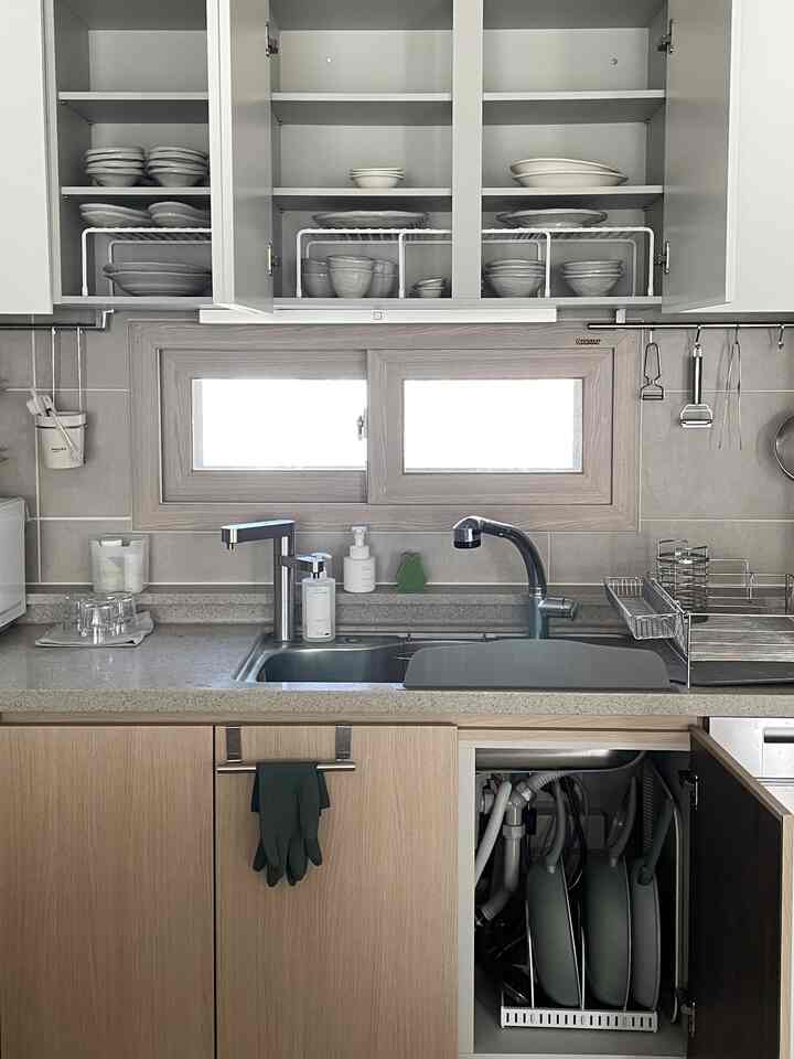 ホワイトとウッドトーンのキッチン、整理された食器棚とフライパンが見える実用的な空間