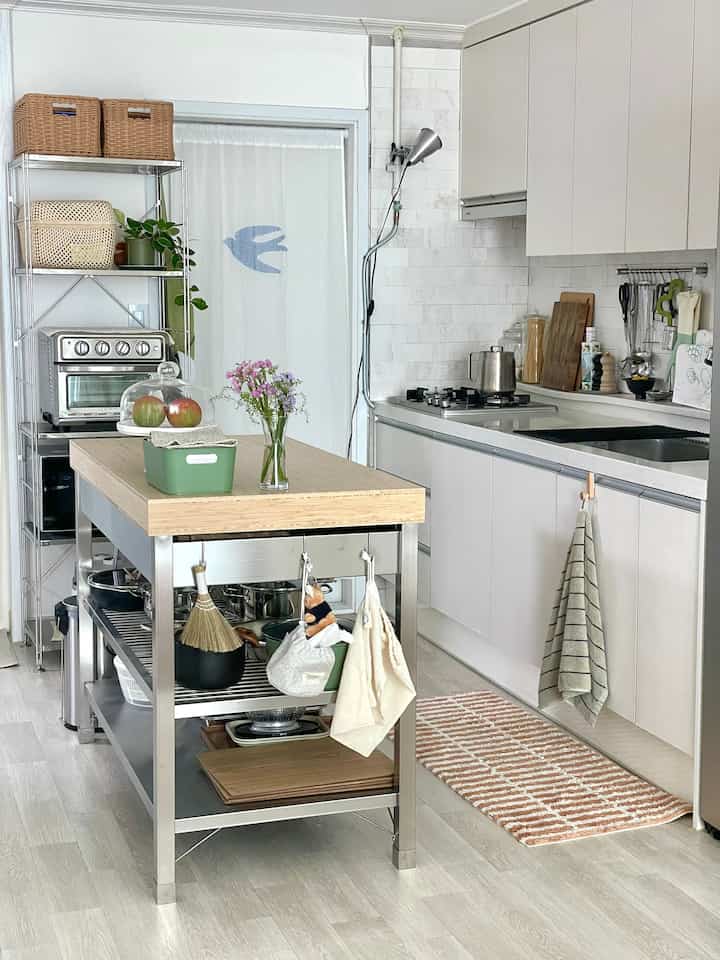 ナチュラルな色調のキッチン、木目調のキッチンアイランドと収納棚が整然と配置された雰囲気のあるインテリア