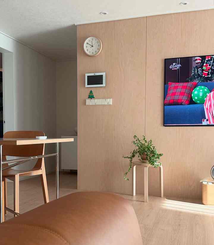 ナチュラルな木目調の壁とソファ、ダイニングテーブルが配置された落ち着いた雰囲気のリビング