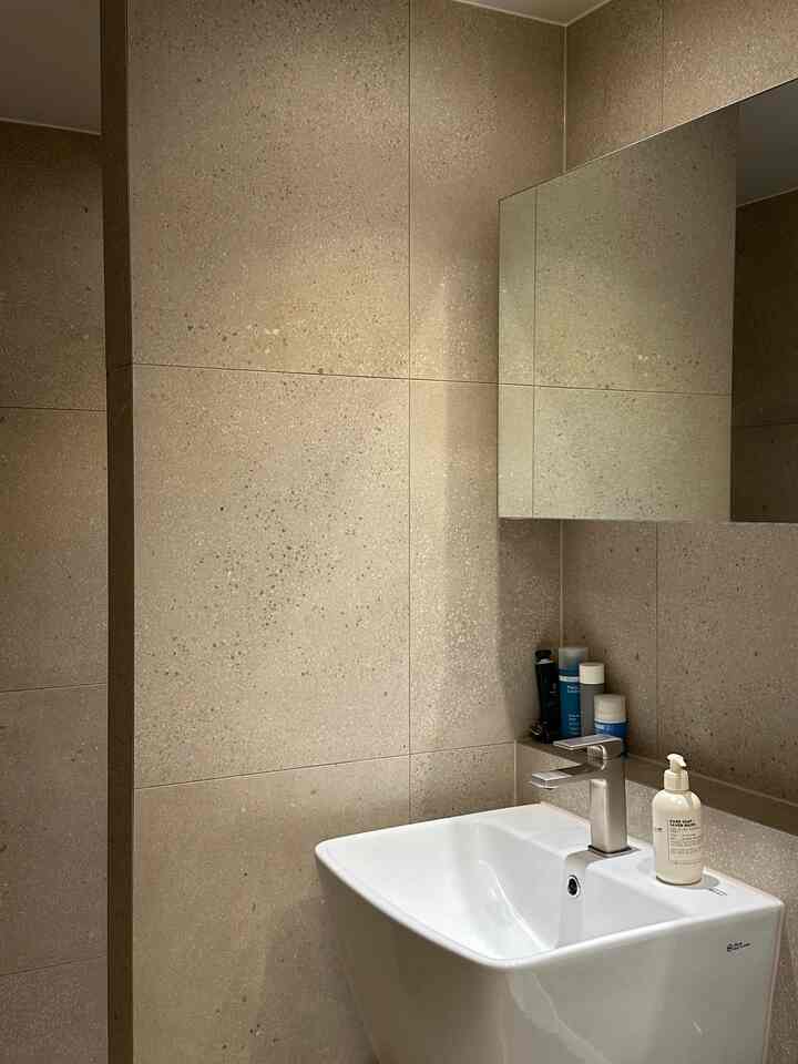 ベージュのタイルと白い洗面台が配置された、清潔感のあるモダンなバスルーム空間