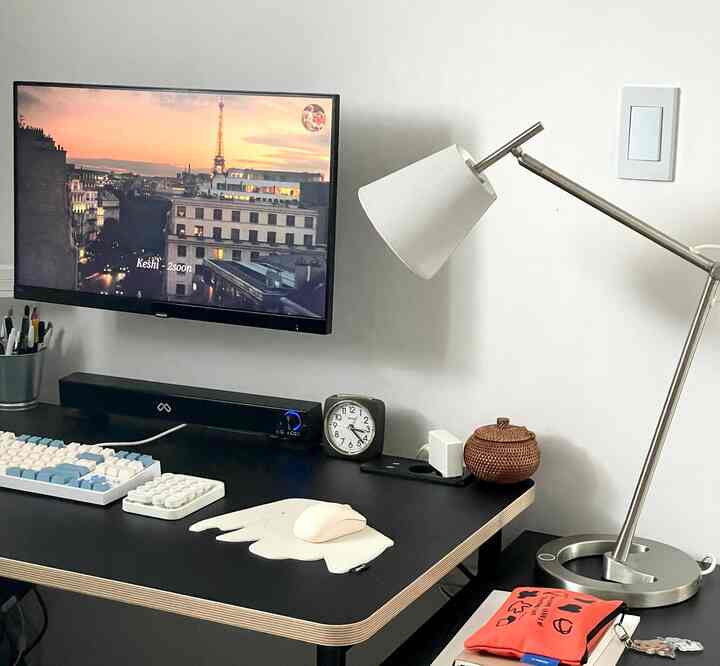 白と黒のトーンでまとめられたコンパクトなホームオフィス、机、テーブルランプ、時計、マウスパッドが配置された整った作業空間