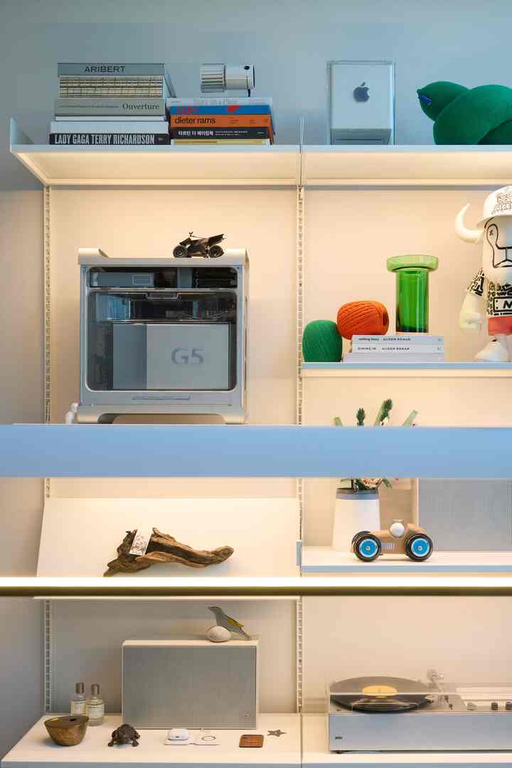 ホワイトとブラウンのトーンのリビング棚、ヴィンテージのオブジェと照明が調和した空間