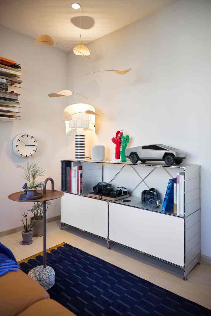 白と青の色調が特徴の書斎、モダンなサイドテーブルと収納棚、壁時計やアートオブジェが配置された印象的な空間