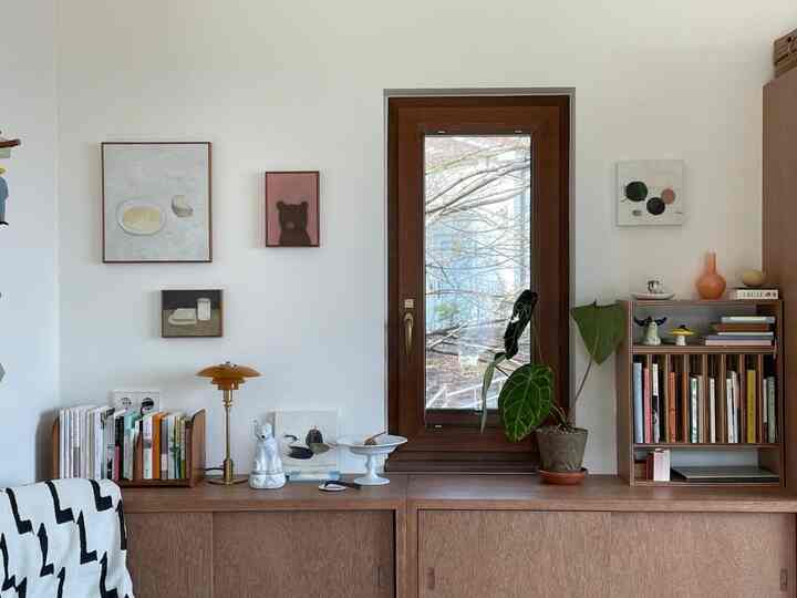 ナチュラルカラーの落ち着いた印象のコンパクトな部屋、木製家具と絵画、植物が配置された空間