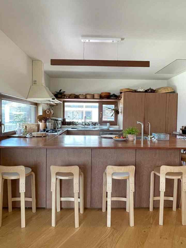 ナチュラルな木目調のキッチン空間、木製のアイランドとカウンタースツールが配置された温かみのあるインテリア