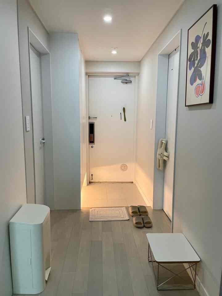 白を基調とした玄関、シューズラックと小さなテーブルが配置された清潔感のあるミニマルな空間