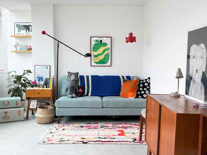 明るいホワイトの壁と木製家具が調和するリビング、ミディアムサイズのブルーのソファと様々なヴィンテージオブジェが配置された温かみのあるインテリア