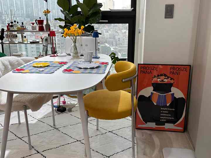 白と黄色の色調のダイニングルーム、ダイニングテーブルと椅子、ラグ、観葉植物が配置された雰囲気のある空間