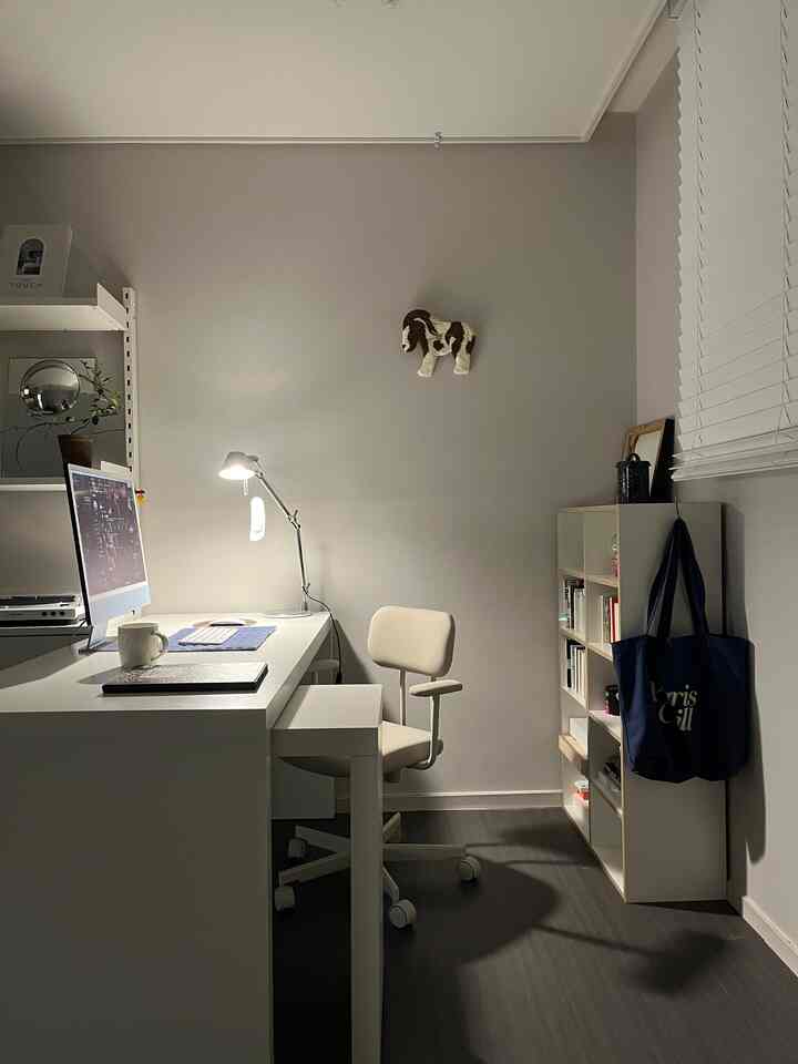 白とグレーのトーンのホームオフィス、シンプルなオフィスチェア、デスク、本棚が配置された清潔感のある作業空間