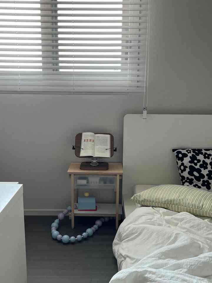 ホワイトとベージュ調の寝室、木製ナイトテーブルと読書台が配置されたシンプルで落ち着いたインテリア