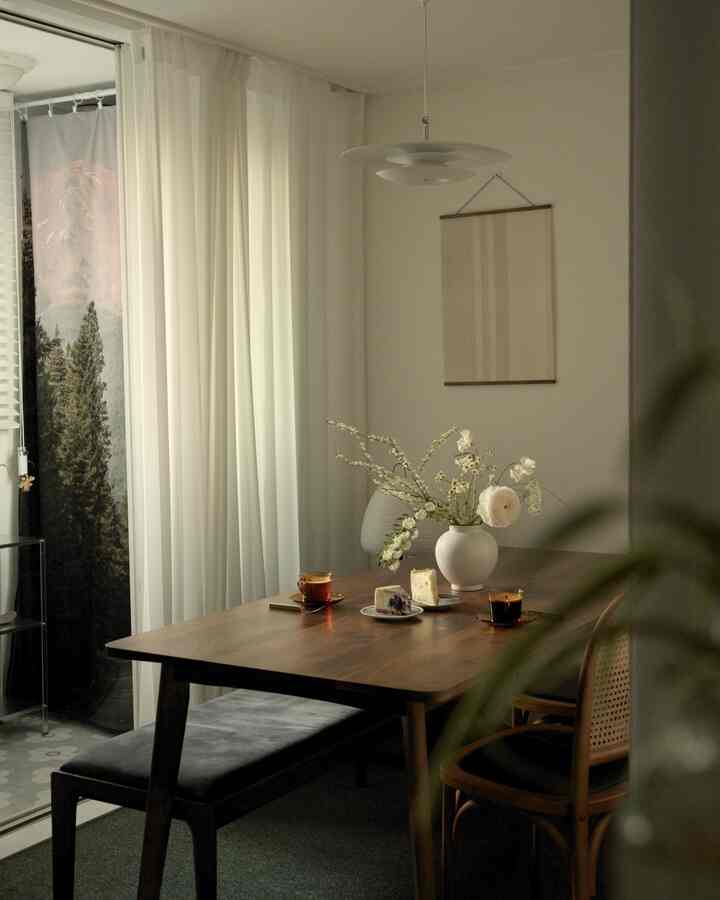 白い壁とカーテン、木目調のダイニングテーブルとベンチが配置されたナチュラルモダンなダイニングルーム