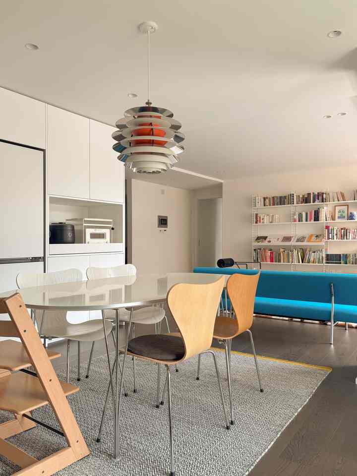 白とグレーのトーンのモダンダイニング、青いソファと白い本棚が配置された雰囲気のあるインテリア