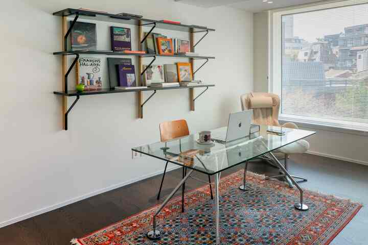 白い壁と茶色の床、デスクとオフィスチェアが配置された清潔感のあるホームオフィス空間