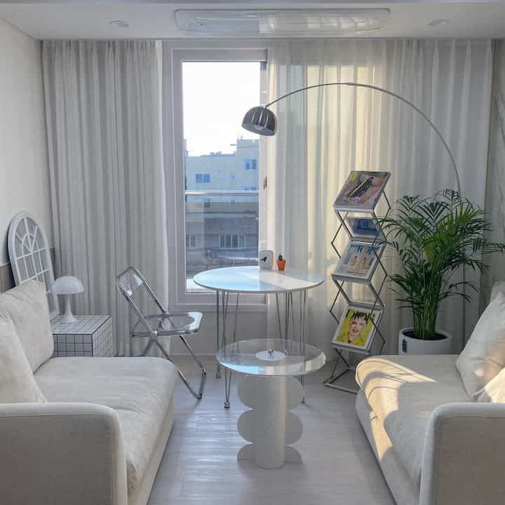 白とシルバーのトーンのリビング、中央のラウンドテーブルと向かい合うソファが配置された、清潔感とモダンな雰囲気のあるインテリア